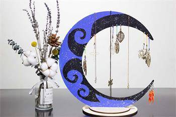 a laser cut photo of a purple and black crescent moon shaped stand holding necklaces and jewelry