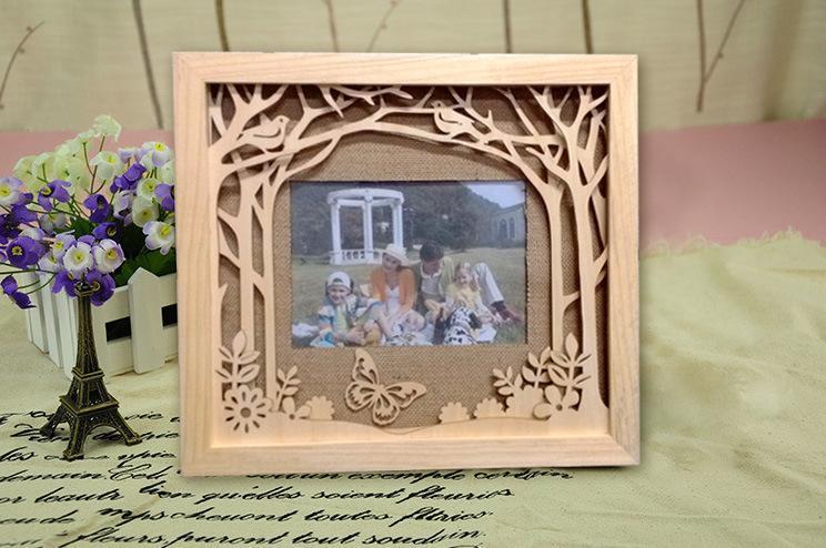 a photo of a wooden laser cut photo frame. It interior of the fram has trees laser cut out of thick cardstock whith a photo of a family inside