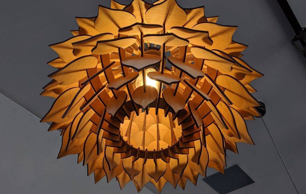 a laser cut hanging wood lighting fixture with wooden pieces that look like pedals expanding out from the center. Made on a Thunder Laser in Canada