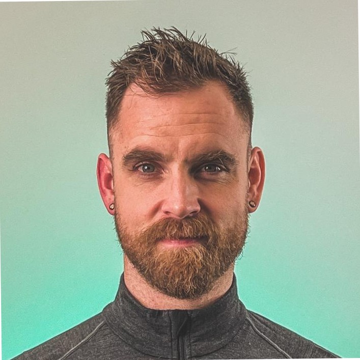 a headshot of a light skinned man with a short spiky hair cut and a short beard and moustache.