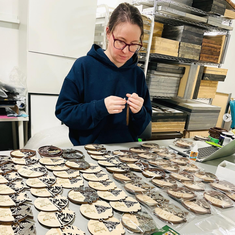 Danelle a woman with dark hair and glasses assembling christmas oranments