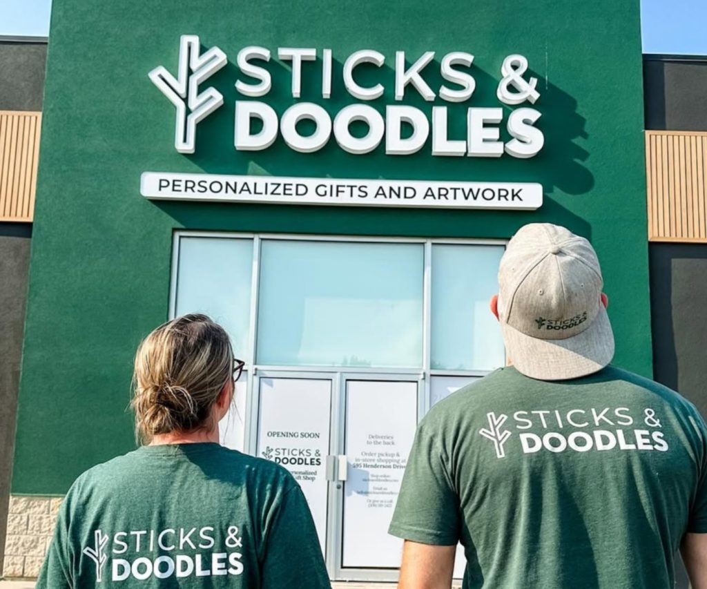 Kyle and Danelle photo from behind as they look up at the green building with their company logo